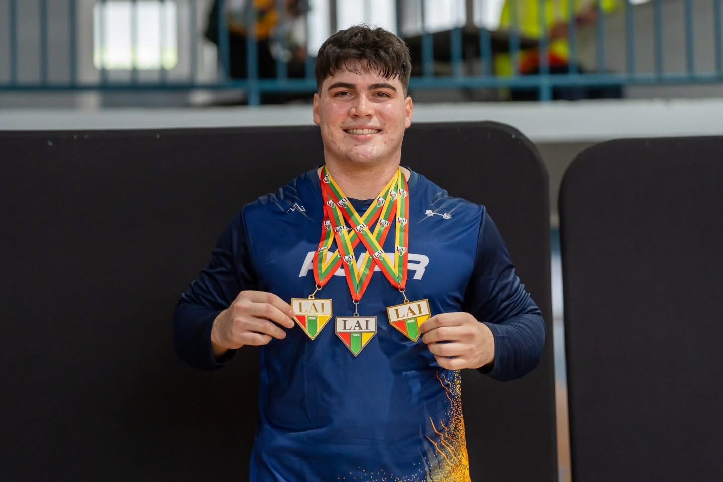 Argenis Vélez smiling and holding three medals